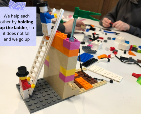 Lego scene with a figurine holding the ladder for another to show support for each other.